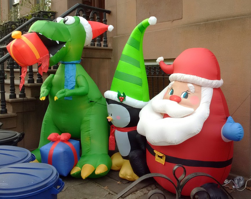 An inflatable dragon with a present, penguin, and Santa Claus outside a brownstone home in Cobble Hill, Brooklyn.