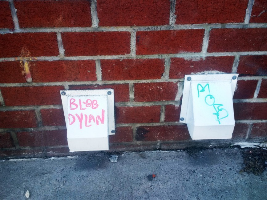 "BLOB DYLAN" written on a vent in Bushwick next to another vent with illegible writing.