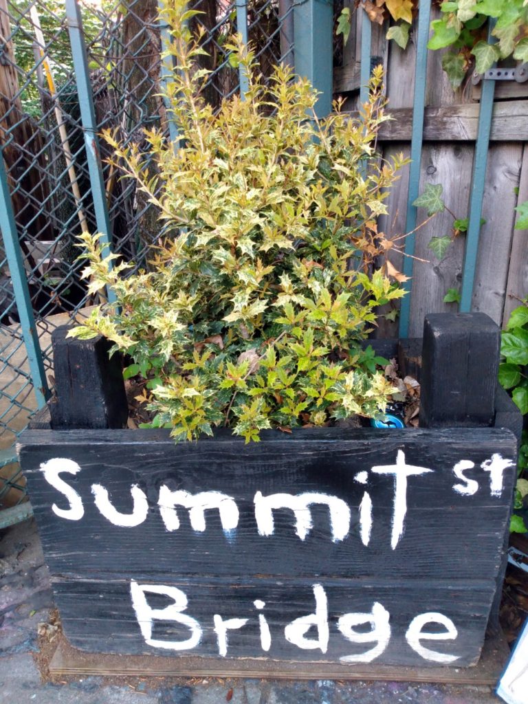 A planter box at the foot of Brooklyn's Summit Street Bridge with the name of the bridge written on it.