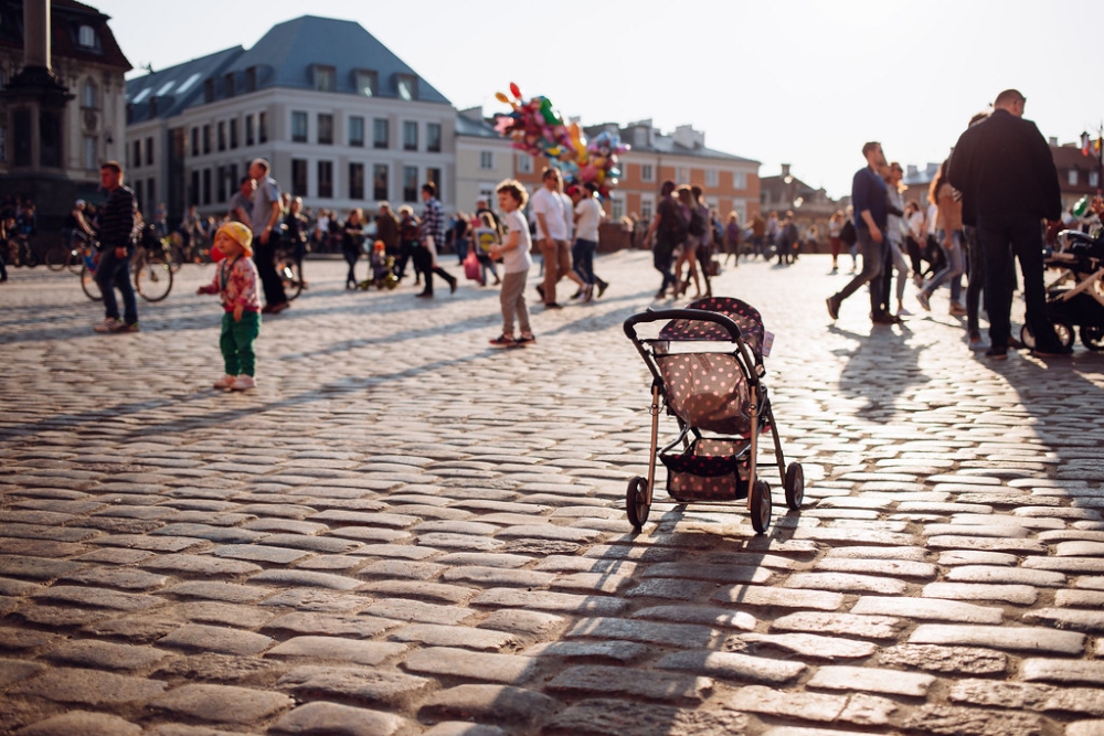 Stock image of a stroller in the middle of a wide town square.