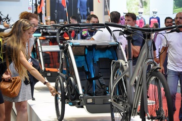 Photo of people at an event looking at bike trailers.  Public domain image courtesy of Pxhere.