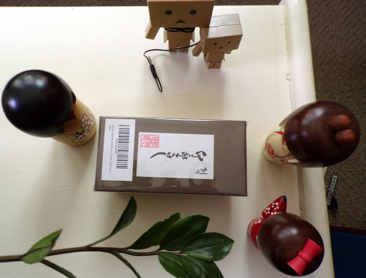 Three Usaburo kokeshi dolls and two danbo surround an unopened Usaburo kokeshi doll box.