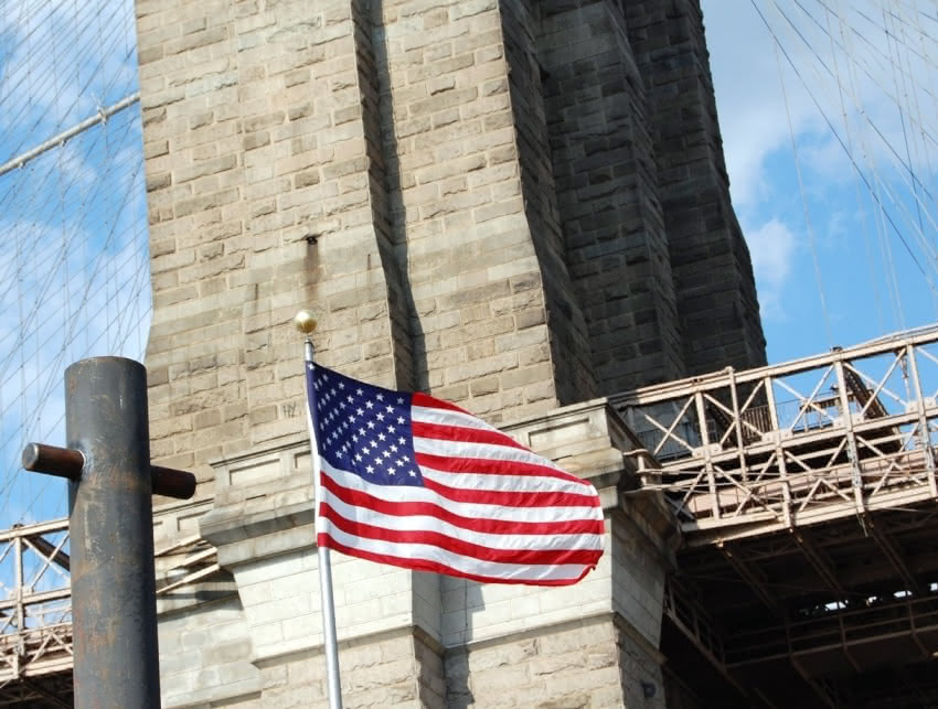 2007 photograph of an American Flag against the backdrop of the Brooklyn Bridge.