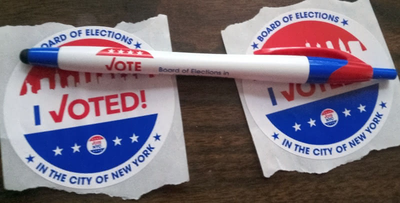 A New York City election pen overlaying two "I Voted!" stickers.