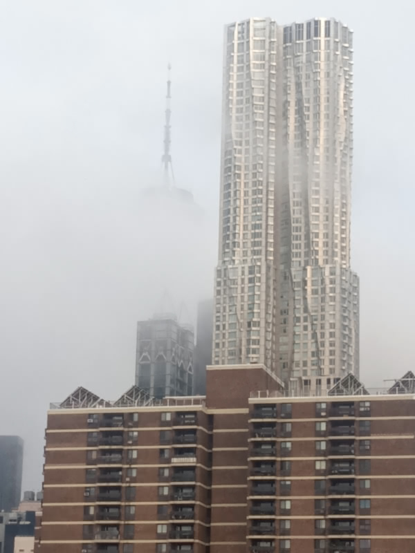 Photo of the Freedom Tower from the Brooklyn Bridge where the Freedom Tower is almost completely covered by fog.