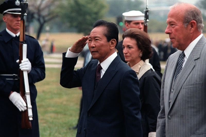 Ferdinand Marcos, seen saluting, in 1982.  To his right is then-Secretary of State George Schultz.
