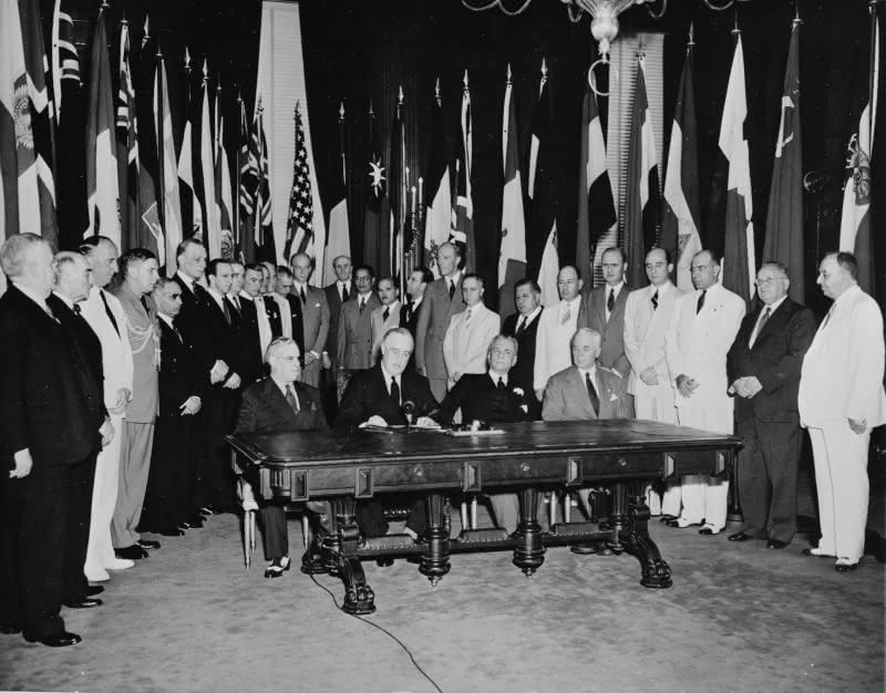 Roosevelt is seated center-left, next to Quezon, seated center-right.  Image taken in 1942 in Washington D.C.  Quezon was leading the Philippine Government in exile due to the Japanese occupation.