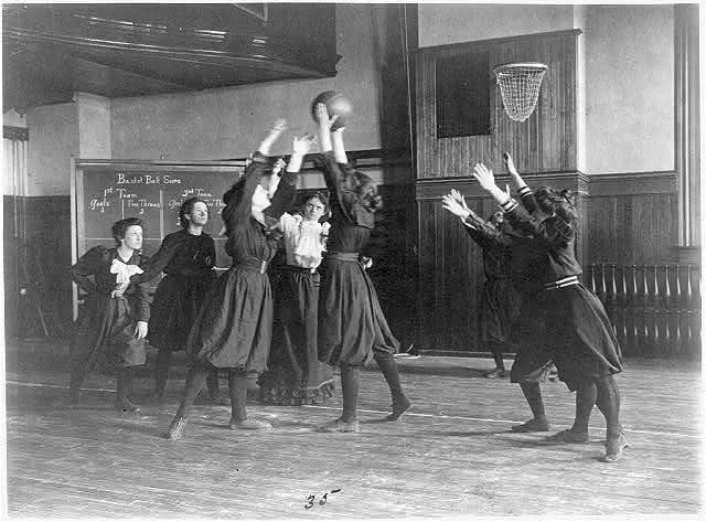 Johnston, Frances Benjamin, photographer. Female students playing basketball in a gymnasium, Western High School, Washington, D.C. Washington D.C, 1899. [?] Photograph. https://www.loc.gov/item/2002695166/.