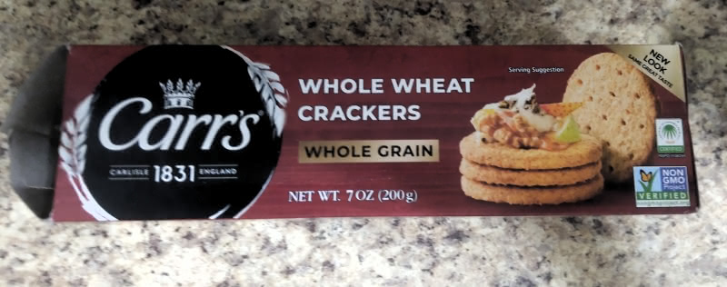 Photograph of a box of Carr's brand Whole Wheat Crackers. The Carr's logo is on the left, the name of the crackers is center, and a photograph of the crackers is on the right. The backdrop of the box is maroon.