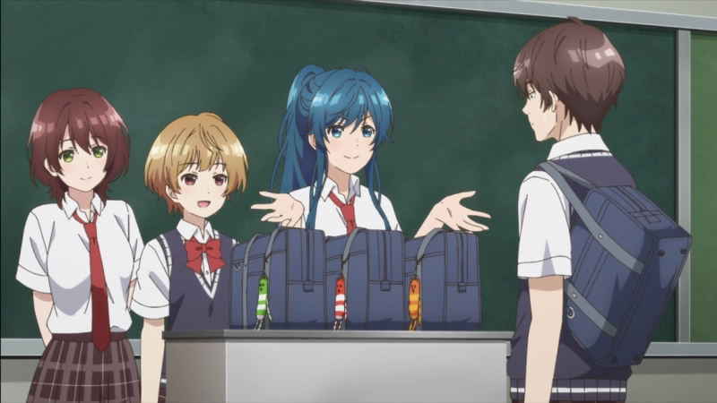 Hinami, Tama, and Mimimi stand behind the teacher's desk with a blackboard behind them. There are three bags on the desk with almost-matching decorations being presented by Mimimi. Tomozaki looks on while standing on the other side of the desk.