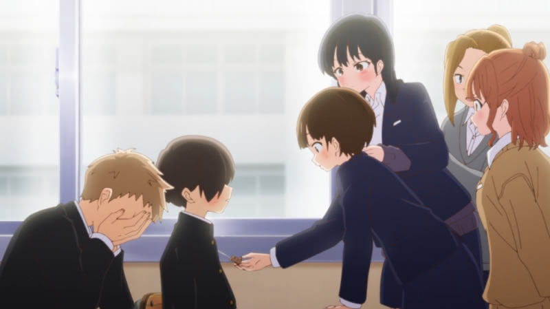 Kyoutarou is sitting at a desk in the first episode of season 2 of The Dangers in My Heart with his arm in a cast. Chihiro Kobayashi is examining his dog keychain. They are surrounded by Shou Adachi, Anna Yamada, Moeko Sekine, and Serina Yoshida.