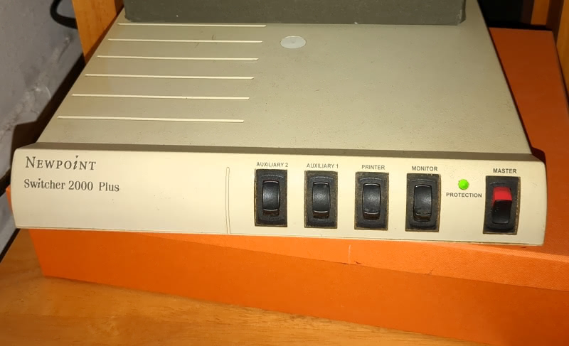 Pictured is a Newpoint Switcher 2000 Plus powerstrip. It is a flat rectangle and the color is a slightly yellow tinted off-white. It has five switches. The one on the far right is flipped on.