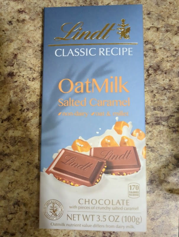 Bar of Lindst Salted Caramel Oatmilk Chocolate in its package on a kitchen counter.