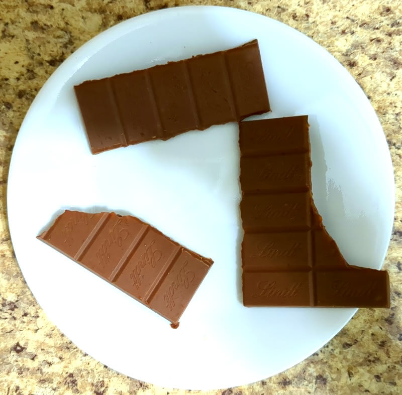 Three slabs of Lindt Salted Caramel OatMilk Chocolate on a white plate.