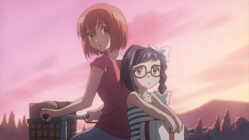 Karada riding a bike with Shouko, with back to Karada, sitting on the back. Both have their heads turned and are looking at something. The reddish-purple late afternoon sky is behind them.