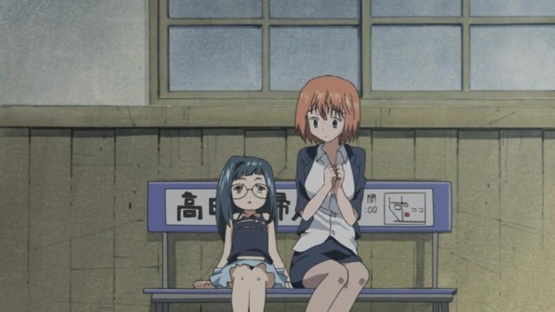 Child Shouko leans back on a bench while a nervous adult Karada, wearing Shouko's clothes which are a bit tight on her, says something.