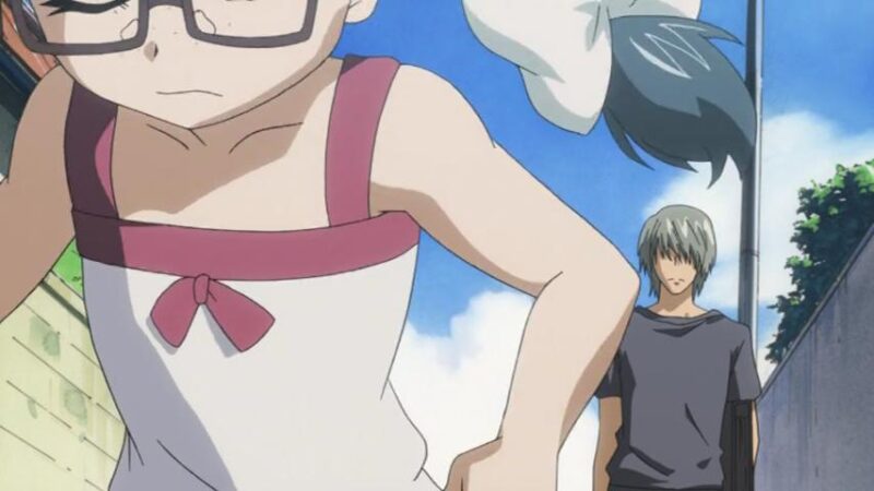 Shouko, running away from Hiro, is in the immediate foreground, as Hiro looks on in the background.