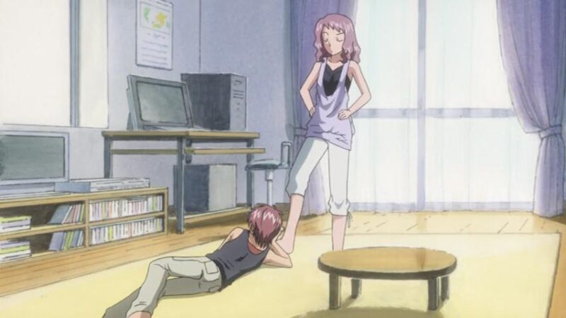 Touko nudges Tetsu, who is laying on her floor, with her foot.