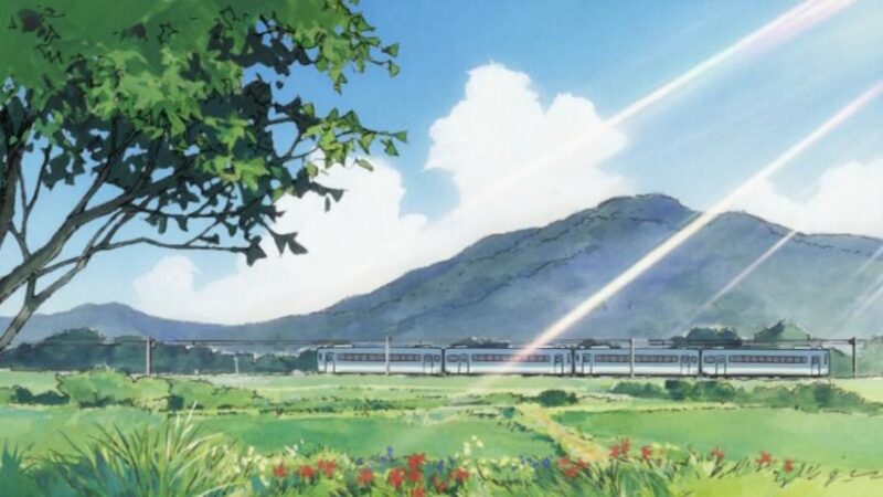 A train with a mountain and sunbeams in the background.