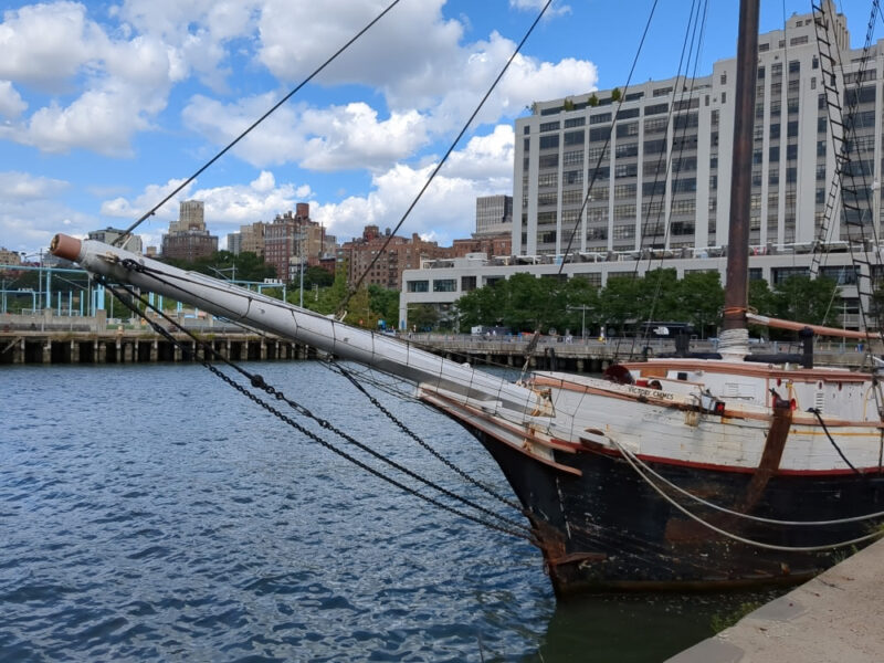 Close-up shot of the bowspirit of Victory Chimes with Brooklyn Bridge Park in the background.